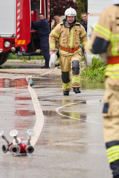 Firefighter Carrying Hose Reels Near Fire Truck During Emergency Response And Team Rescue Operation