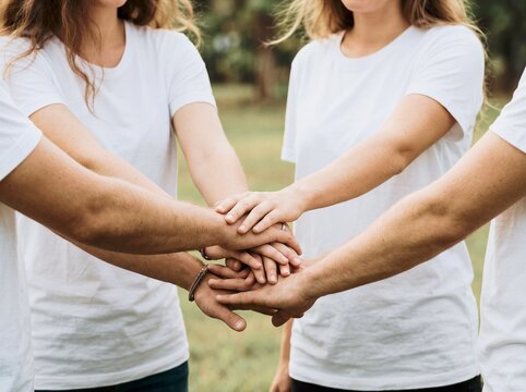 Close up of diverse people stacking hands in unity outdoors in natural light