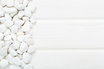 White pebble stones on wooden background, top view © Liami
