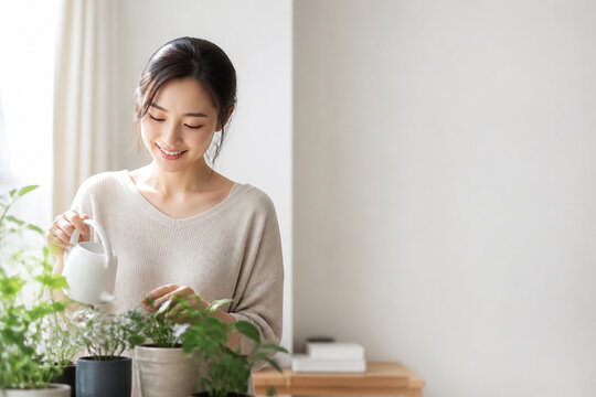 室内で観葉植物に水やりする笑顔の日本人女性のライフスタイル