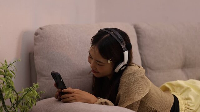 Asian Woman Relaxing at Home Using Smartphone While Listening to Music