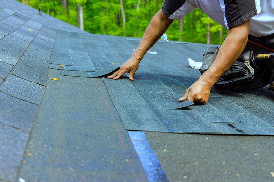 Roofing work is done on house in wooded area