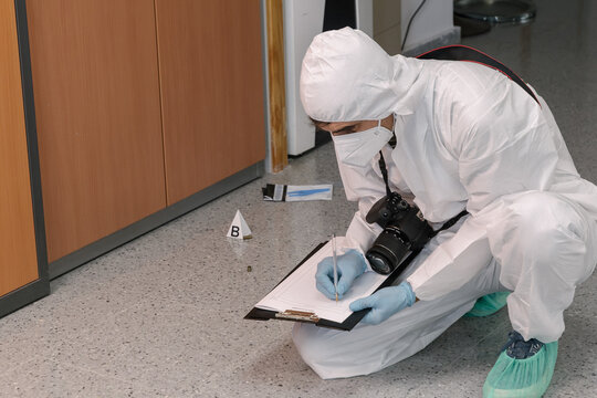 Forensic investigator recording evidence on a clipboard