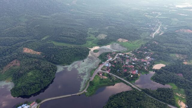 Aerial view shows a small village surrounded by dense forests and waterways at Tasik Raban
