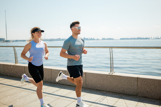 Couple enjoys a sunny morning run along the waterfront promenade