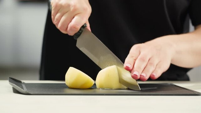 Woman cutting potato on table in kitchen