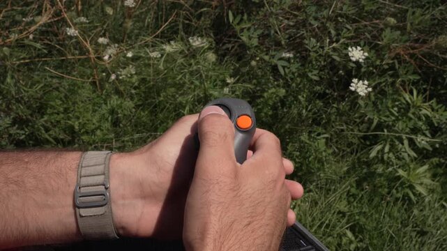  a man using a compact remote controller to operate a drone, focusing on precise joystick movements and wireless flight control. Concept of modern technology, aerial navigation, and drone operation