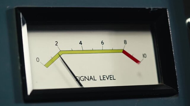 Analog dial indicator of audio signal level amplifier. Vintage arrow moves with sound level. Round classic volume indicator with yellow backlight, VU meters. Close-up of old measuring dB decibels
