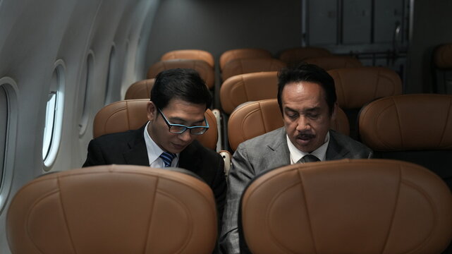  businessman with suit sitting  inside airplane near the window