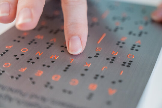 A blind woman learns the English alphabet from a braille sign.