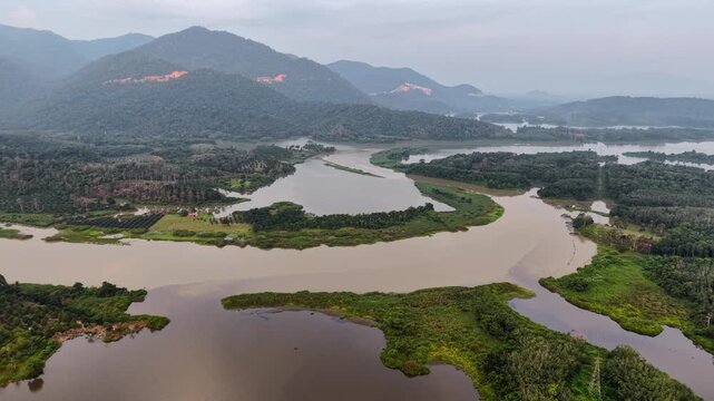 Aerial drone shot captures a meandering river through verdant valleys at Tasik Raban