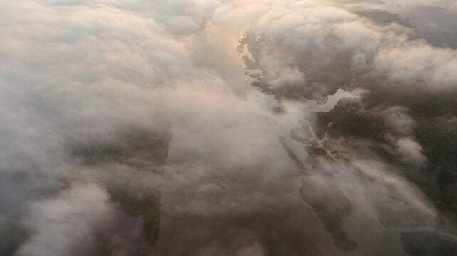 A tranquil aerial view of a river winding through dense clouds and mist at Tasik Raban