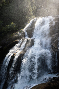 Sunlit waterfall cascading through a forest in British Columbia