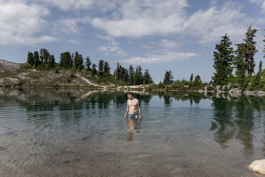 Man wading in a clear alpine lake in British Columbia
