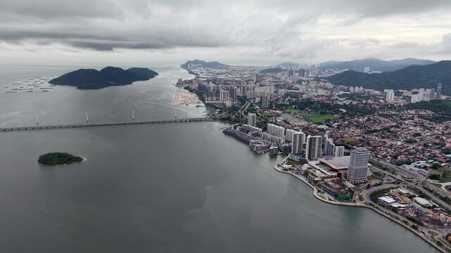 Sky over city meets sea and hills. Grey clouds hover above urban sprawl