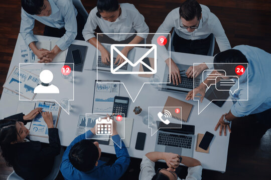 Group of Professionals Engaged in Team Meeting with Digital Communication Icons and Graphs on Table in Modern Office Environment. Sentient.