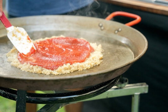 Preparing traditional paella with sofrito in large pan