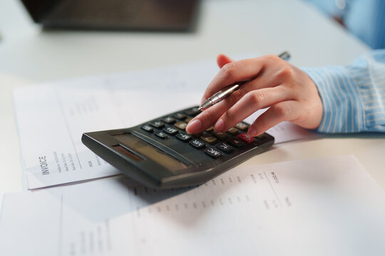 Close-up Accountant verifying financial billing statements with a pen and calculator, certified public accountant services, corporate tax compliance, forensic accounting, statutory audit diligence
