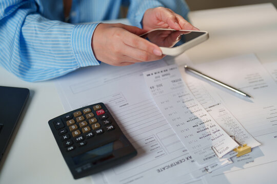 Auditor reviewing client tax certificates and business expenses, calculator, smartphone at a clean workstation, certified public accountant services, tax compliance, forensic accounting diligence