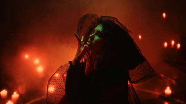 Halloween Witch casting a spell with candles during an exorcism ritual, scary sorceress in Halloween costume performing dark magic, spooky horror movie atmosphere.