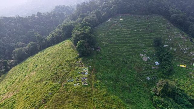 Aerial view captures a green hillside cemetery. Lush grass covers the slopes at Kampar