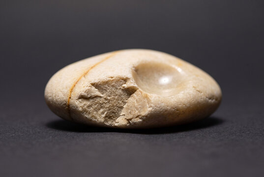 Calm worry stone with smooth polished depression on dark background