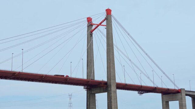 Wide angle video of a massive cable-stayed bridge crossing a wide river under an overcast sky