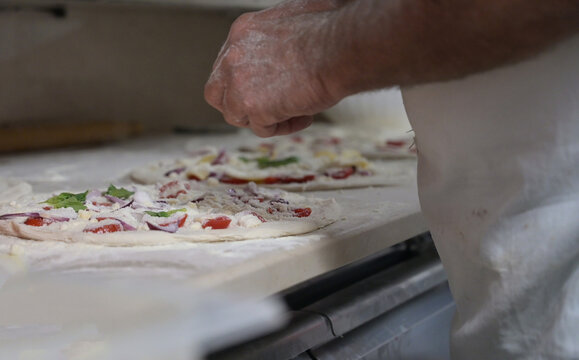 pizzaiolo prepara le pizze sul bancone di una pizzeria