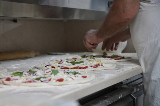 pizzaiolo prepara le pizze sul bancone di una pizzeria