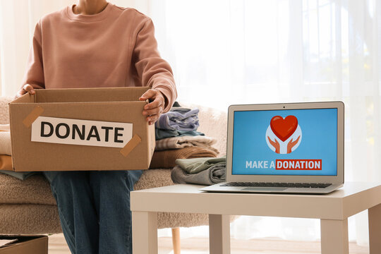 Charity and donation drive, person holding cardboard box with clothes for humanitarian aid and online fundraising website on laptop screen at home