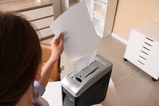 Data privacy and document security, woman shredding confidential paper documents in office to prevent identity theft and protect sensitive information