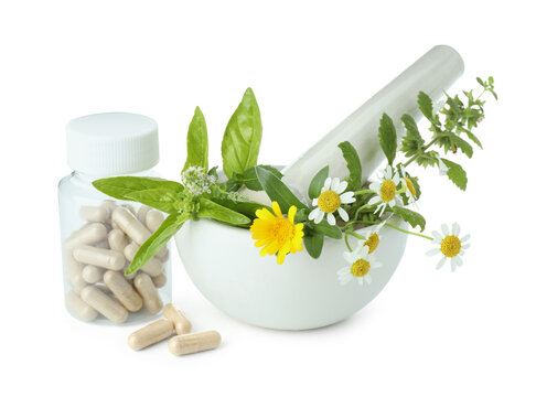Mortar with pestle, herbs and capsules isolated on white