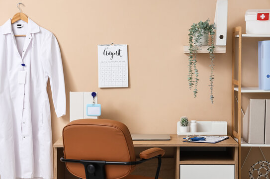 Doctors workplace with laptop and flip calendar on beige wall in medical office