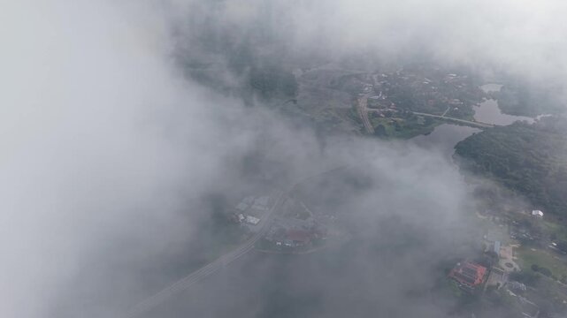 Aerial view of lake landscape partially covered with dense fog and mist, featuring a bridge connecting two land areas at Tasik Raban