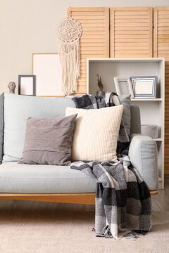 Stylish interior of living room with grey sofa and folding screen