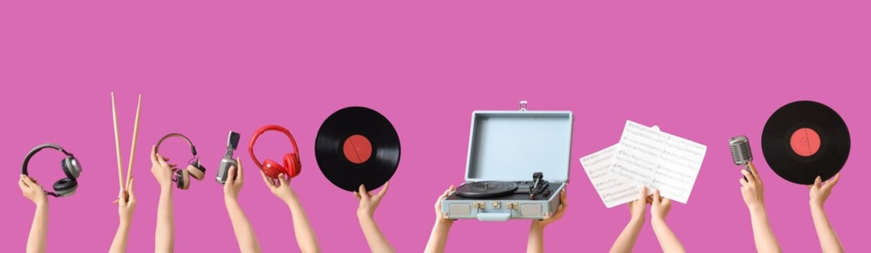 Music culture and entertainment, hands holding vintage record player and musical instruments on a pink background