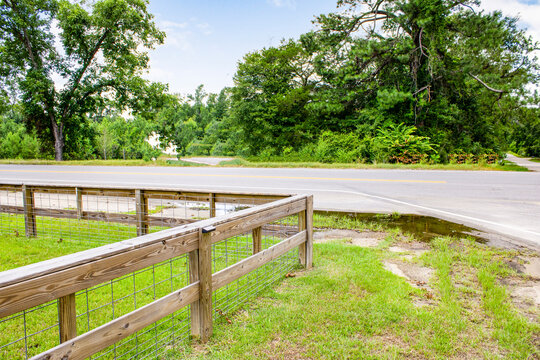 Wooden fence alongside country asphalt road with grassy verge landscape countryside exterior transportation infrastructure pavement environment structure protection boundary property