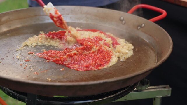 Chef cooking spanish paella sofrito outdoors