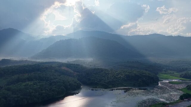Sunlight beams cut through clouds over mountain ranges at Tasik Raban