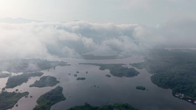 Aerial view shows misty lakes and islands. Early morning light shrouds the landscape at Tasik Raban