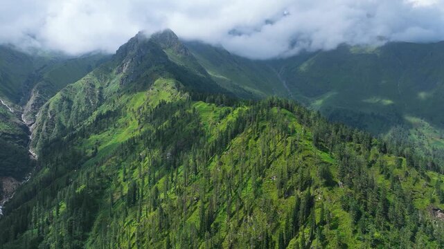Drone hyperlapse capturing dynamic clouds drifting across rugged Himalayan peaks surrounding the Kheerganga and Tosh trekking corridor, India.