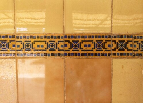 Yellow ceramic wall tiles with dark blue geometric patterns and vintage decorative border. Ideal for interior design projects. Ideal for vintage style decor.