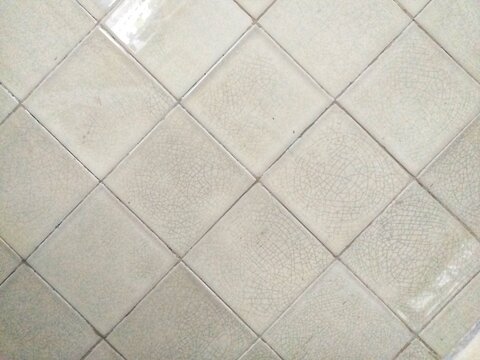 White ceramic tiles with a geometric grid pattern suitable for kitchen and bathroom walls and floors. Ideal for interior design projects.
