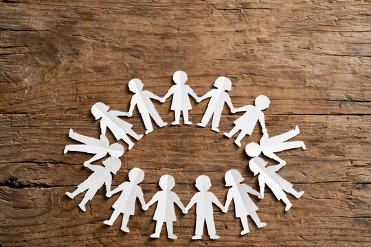 Paper cutout of a family displayed on a wooden table, symbolizing unity for World Children's Day celebrations