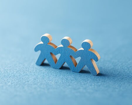 Blue wooden human figures linked together on blue background representing unity and teamwork in professional or social connection concept