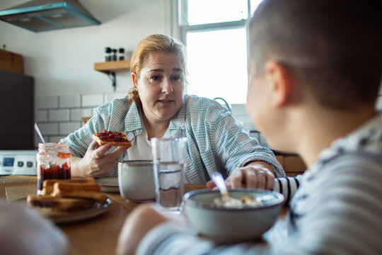 Mother talking with son at breakfast in home kitchen