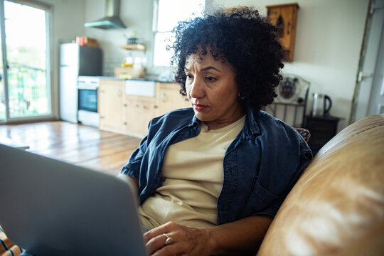 Middle-aged woman working on laptop in home kitchen