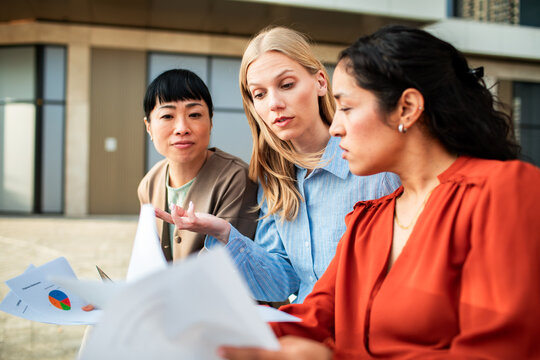 Diverse businesswomen reviewing charts outside an office