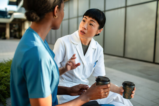 Healthcare workers discussing case over coffee outside hospital