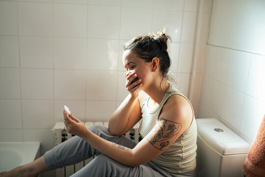Young woman reacting to pregnancy test in bathroom